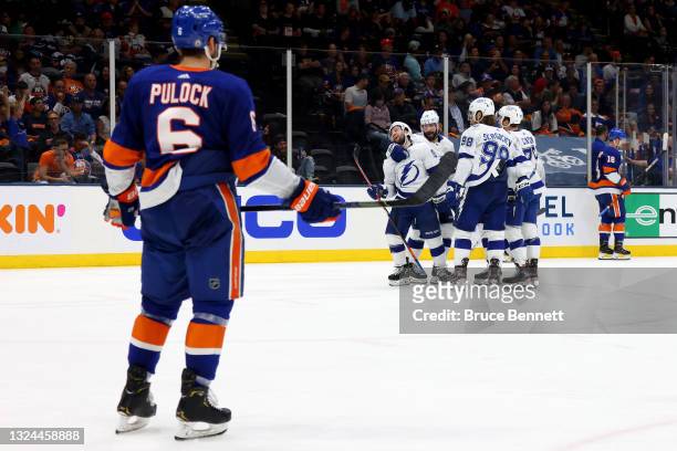 Ryan Pulock of the New York Islanders watches as Tyler Johnson of the Tampa Bay Lightning celebrates his goal with Curtis McElhinney, Mikhail...