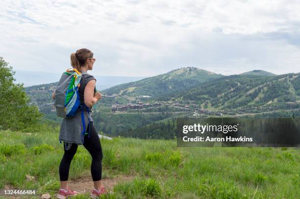 athletic woman hiker admiring the view of mountains and ski areas surrounding park city utah - utah stockfoto's en -beelden