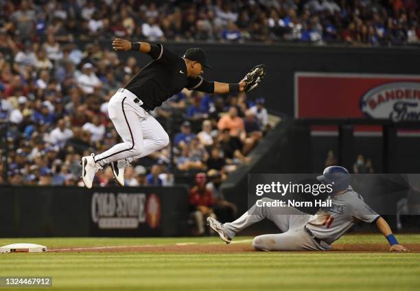 Eduardo Escobar of the Arizona Diamondbacks makes a leaping catch on a wild throw from Christian Walker as AJ Pollock of the Los Angeles Dodgers...