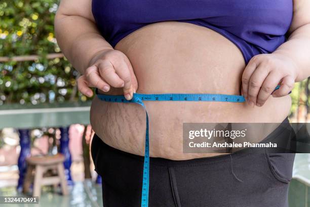 diet concept: close up picture of fat lady measure her waist with white background - fat loss training stockfoto's en -beelden