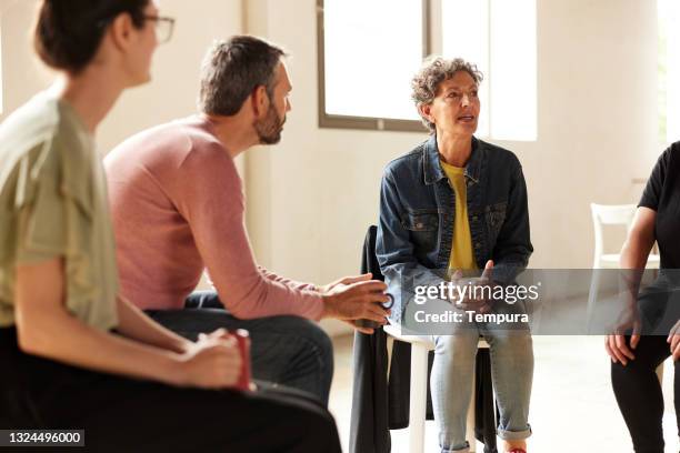 a depressed woman talking to the other members of the therapy group. - aa meeting stock pictures, royalty-free photos & images