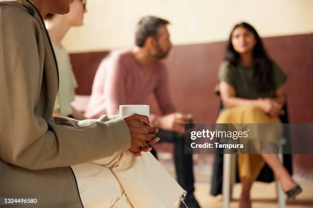 clow-up view of hands holding a cup of coffee at group therapy. - group therapy 個照片及圖片檔