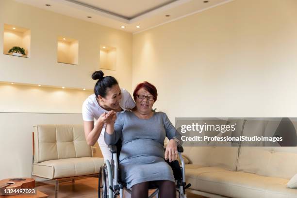 senior woman in wheelchair is happy to have a caregiver by her side. - hospital visit stock pictures, royalty-free photos & images