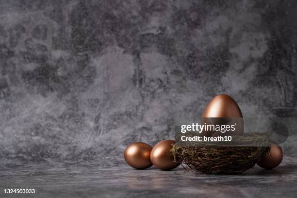 financial concept. golden eggs in hay nest on dark background. - easter egg imagens e fotografias de stock