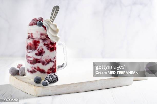 raspberries yogurt smoothie overflow with frozen berries - strawberry and cream stock pictures, royalty-free photos & images