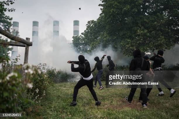 Protestors throw objects as they clash with French police after a memorial march for French teenager Nahel, shot by police during a traffic control...