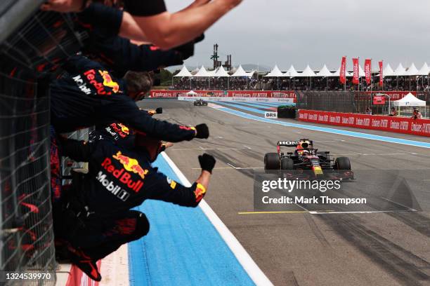 Red Bull Racing team members celebrate on the pitwall as Max Verstappen of the Netherlands driving the Red Bull Racing RB16B Honda crosses the finish...