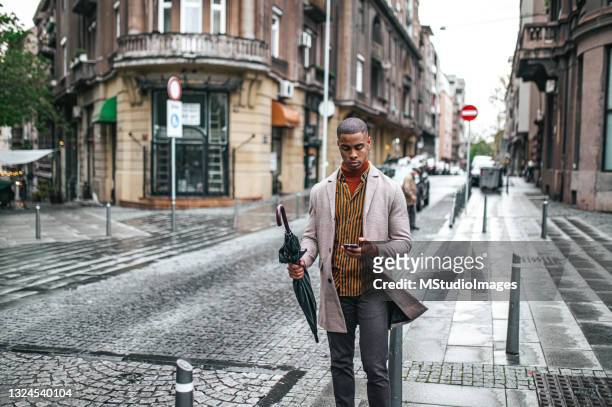 businessman walking down the street and using mobile phone - weather app stock pictures, royalty-free photos & images