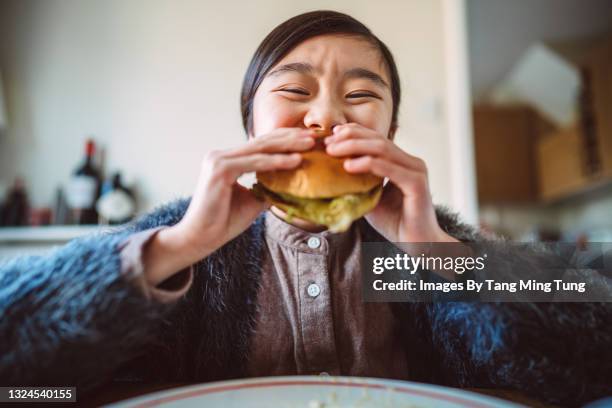 lovely cheerful girl enjoying her homemade burger at home - veggie burger fotografías e imágenes de stock