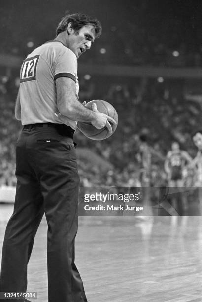Referee Earl Strom holds the ball and glances backward menacingly during an NBA basketball game between the Denver Nuggets and Philadelphia 76ers at...