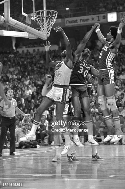 Philadelphia 76ers forwards George McGinnis and Julius Erving compete with Denver Nuggets forward Paul Silas for a rebound during an NBA basketball...