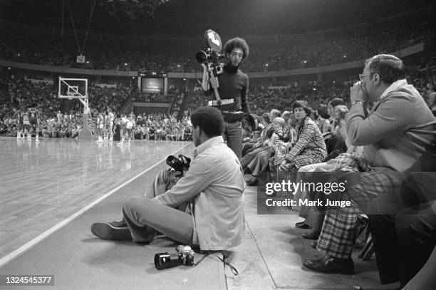 Two photographers, one shooting still images and the other shooting film are working on the sideline during an NBA basketball game between the...