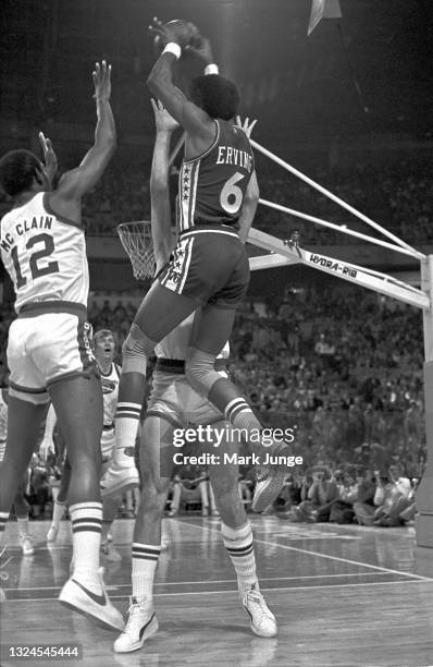 Philadelphia 76ers forward Julius “Dr. J.” Erving skies over Denver Nuggets forward Bobby Jones and guard Ted McClain during an NBA basketball game...