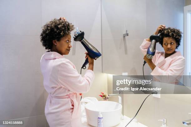 frau kümmert sich um ihre haare im badezimmer - drying hair stock-fotos und bilder