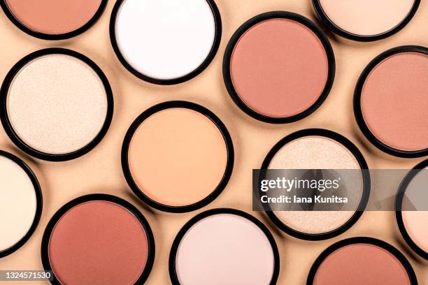 compact face powder, blush, eye shadow on beige background. cosmetic products for makeup, skin care, contouring. top view. - cipria foto e immagini stock