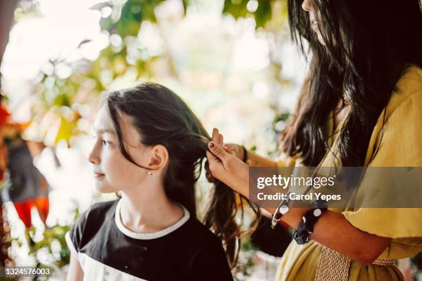 big sister combing braiding littler sister hair at home - big hair stockfoto's en -beelden