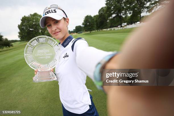 Nelly Korda poses for a simulated selfie with the trophy after winning the Meijer LPGA Classic for Simply Give at Blythefield Country Club on June...