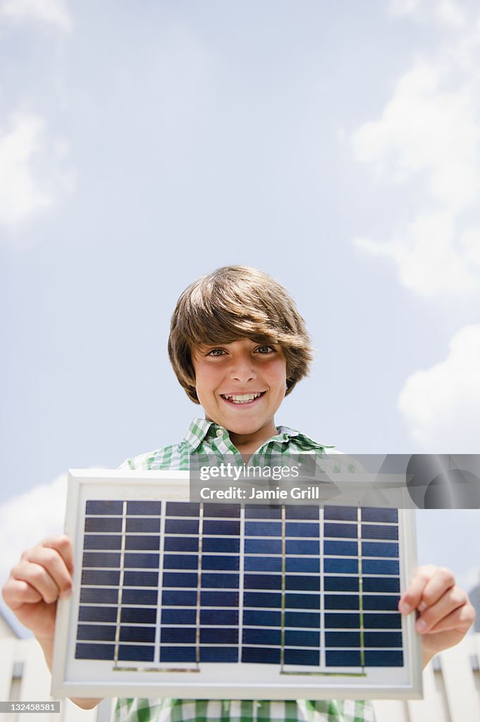 Boy holding solar panel, smiling