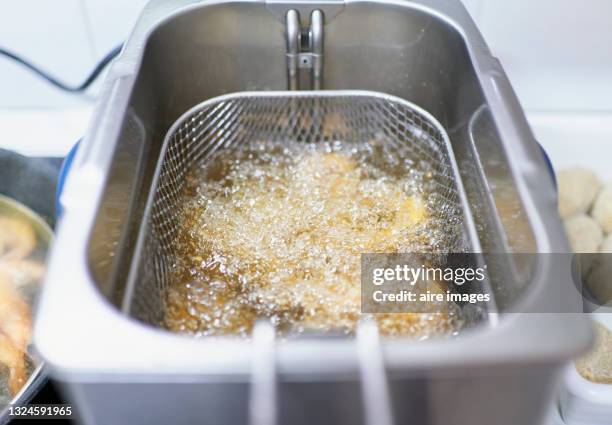 fresh squid rings cooking into the deep fryer. - gefrituurd stockfoto's en -beelden