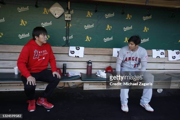 Translator Ippei Mizuhara and Shohei Ohtani of the Los Angeles Angels in the dugout before the game against the Oakland Athletics at RingCentral...