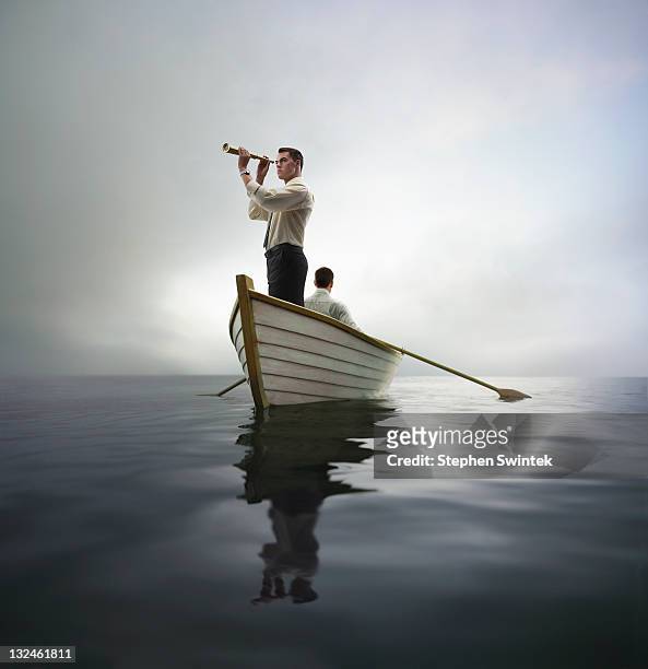 business man looking through spyglass in a boat - bateau à rames photos et images de collection