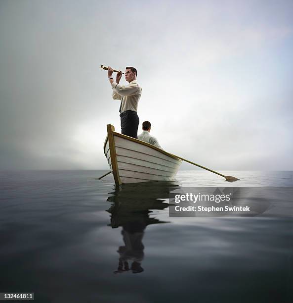 business man looking through spyglass in a boat - homme et longue vue photos et images de collection