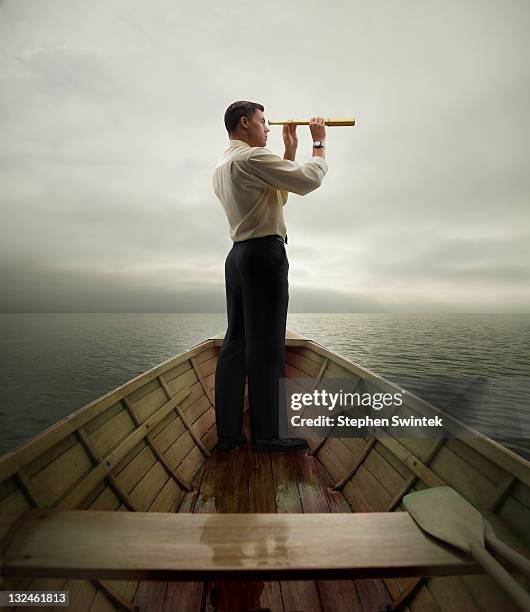 man in boat looking through spyglass - catalejo fotografías e imágenes de stock