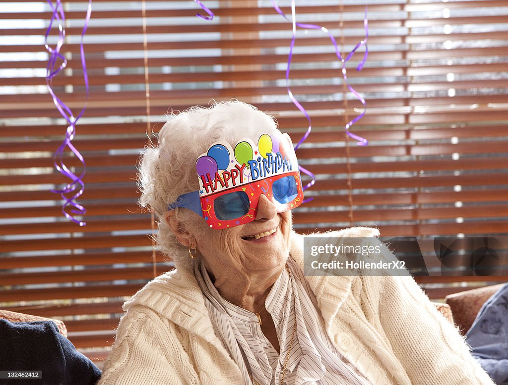 Senior woman with birthday glasses on