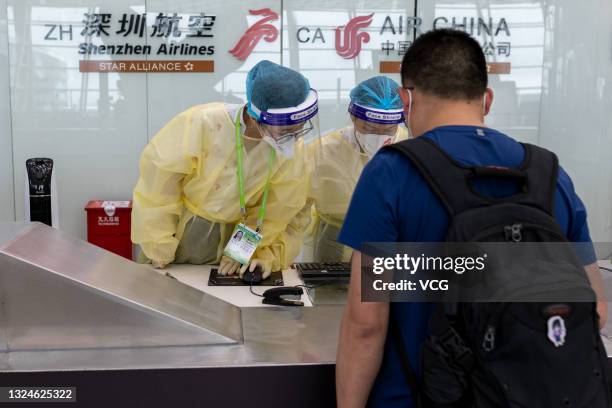 Staff members in protective suits serve a passenger at Shenzhen Baoan International Airport on June 19, 2021 in Shenzhen, Guangdong Province of...