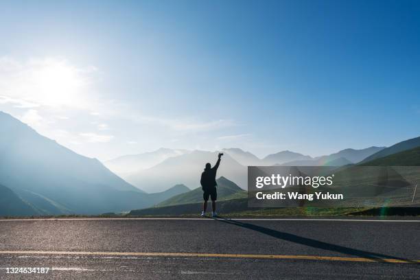 a young man stood on the top of the mountain, silhouetted - success in a majestic sunrise stock pictures, royalty-free photos & images