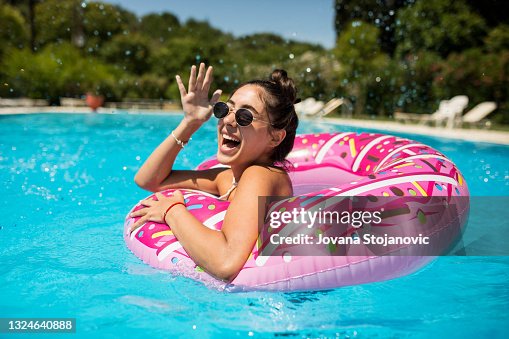 Una hermosa chica en la piscina en un donut inflable se divierte en un caluroso día de verano Una hermosa chica en la piscina en un donut inflable se divierte en un caluroso día de verano