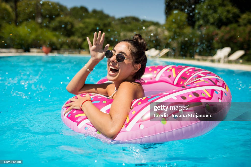 A beautiful girl in the pool on an inflatable donut is having fun on a hot summer day