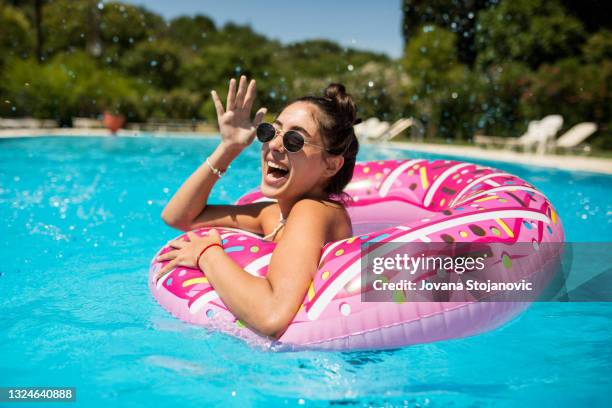 a beautiful girl in the pool on an inflatable donut is having fun on a hot summer day - summer beach bildbanksfoton och bilder