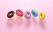 Colorful donuts flying on pink background.