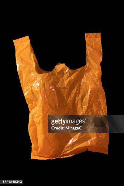 orange colored plastic bag on black - plastic bag stock pictures, royalty-free photos & images