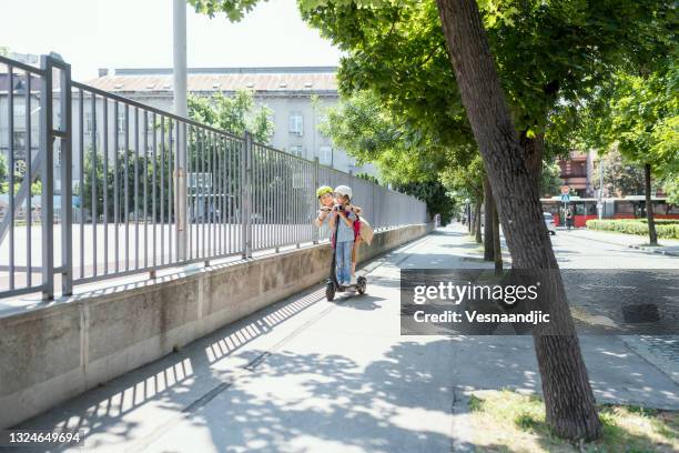 little girl with mother arriving at school on electric scooter - safe kids day arrivals stock pictures, royalty-free photos & images