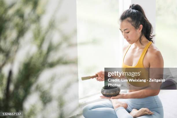 female asian yogi meditating with a singing bowl - rin gong 個照片及圖片檔