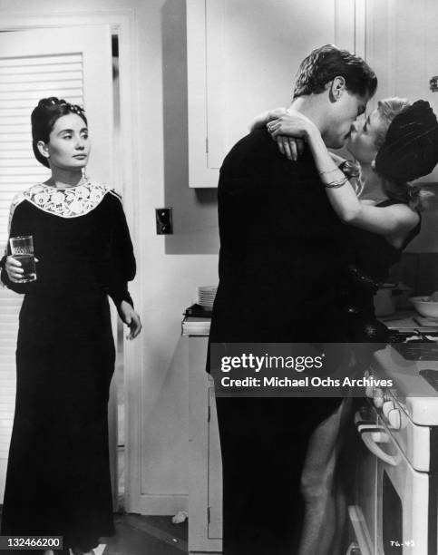As Kathleen Widdoes enters the kitchen she sees Carrie Nye and Larry Hagman sharing kisses in a scene from the film 'The Group', 1966.