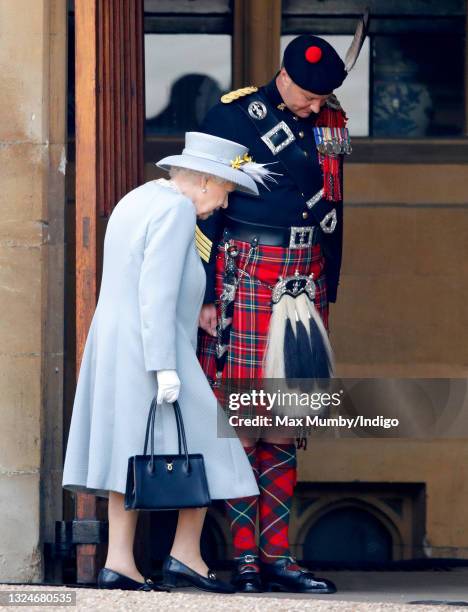 Queen Elizabeth II walks past The Queen's Piper, Pipe Major Richard Grisdale of The Royal Regiment of Scotland as she returns to Windsor Castle after...