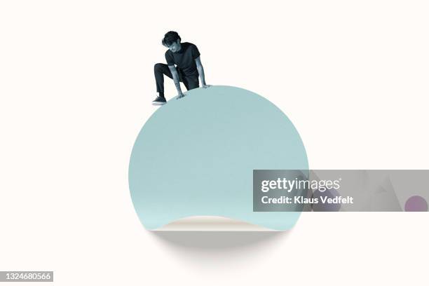 young man climbing on turquoise blue circle - regarder vers le bas photos et images de collection