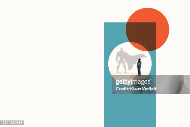 young man standing in front of superhero shadow - superhero shadow stock pictures, royalty-free photos & images