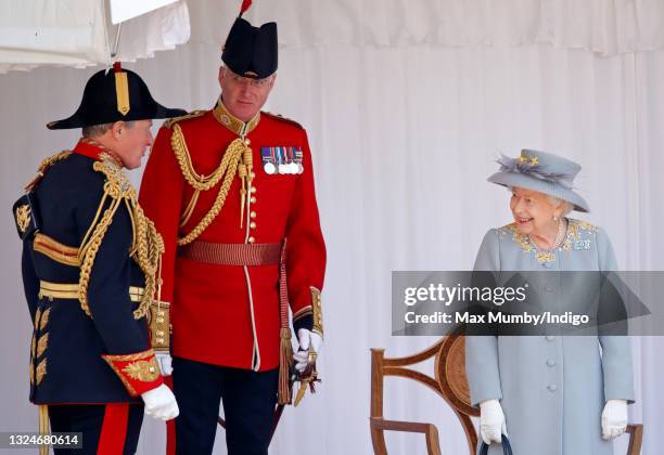 Queen Elizabeth II talks with Crown Equerry Colonel Toby Browne and Lieutenant Colonel Michael Vernon as she attends a military parade, held by the...