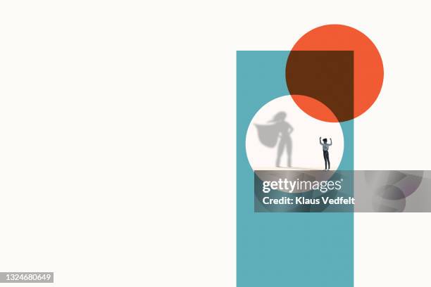 woman flexing muscles in front of superwoman shadow - superhero shadow stock pictures, royalty-free photos & images