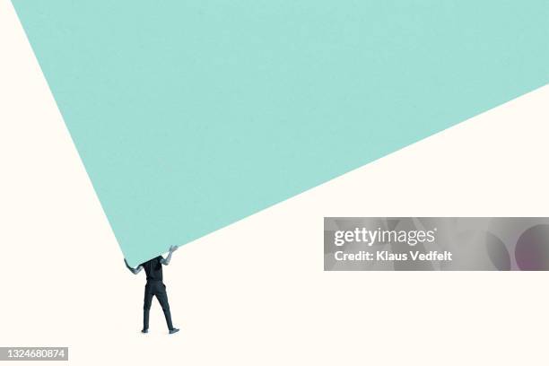 man carrying green wall against white background - over-burdened stock pictures, royalty-free photos & images