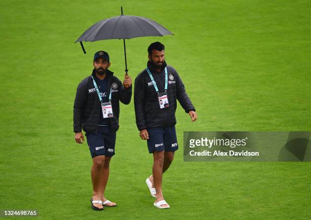 Ajinkya Rahane and Cheteshwar Pujara of India walks across the outfield as play is delayed on Day 4 of the ICC World Test Championship Final between...
