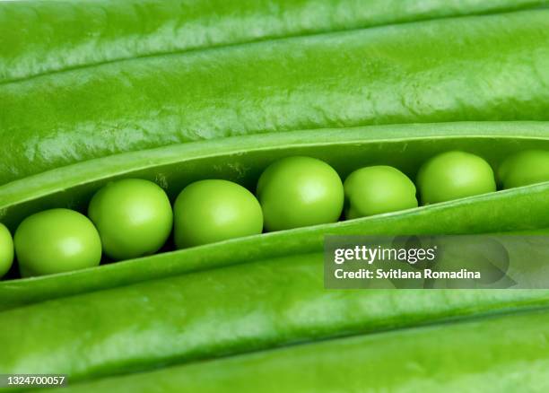 food background with open pea pod with fresh green peas - peas stockfoto's en -beelden