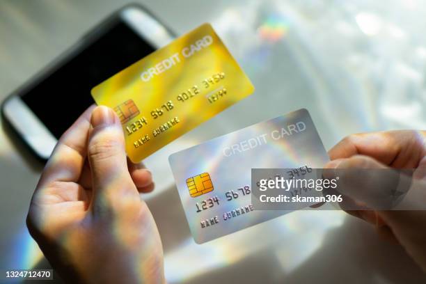 close up hand holding blank credit card  black,gold,platinum color with spectrum light and shadow background - financing stock-fotos und bilder