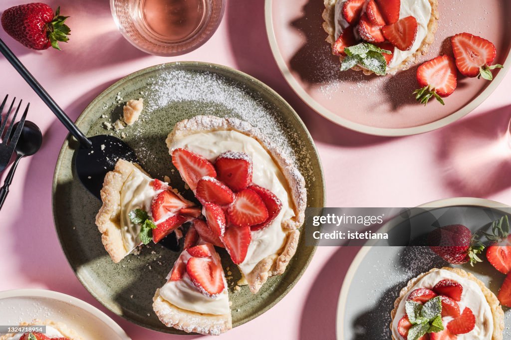 Summer sweet strawberry tarts on pink background with harsh shadows