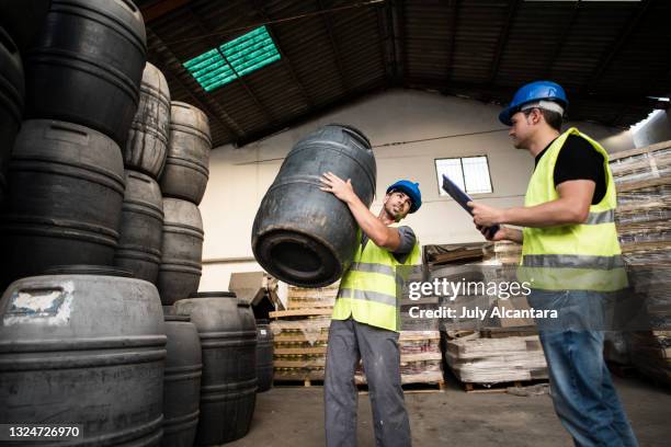 workers transport storage drums during a working day in an industrial warehouse - shovel stockfoto's en -beelden