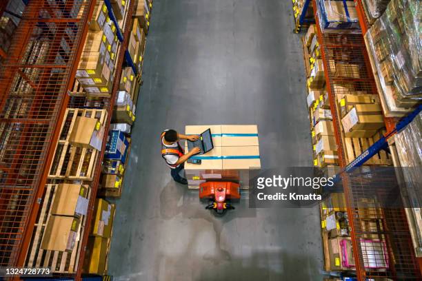 top view of warehouse worker using laptop to check location of goods. - entregar fotografías e imágenes de stock